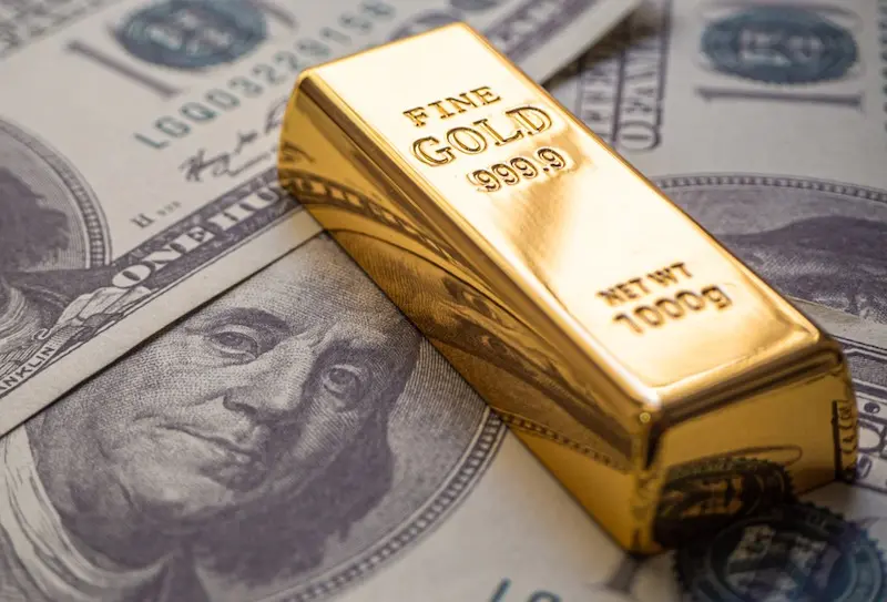 Lingot d'or Fine Gold 999,9 posé sur des billets de cent dollars — liquidité internationale de l'or